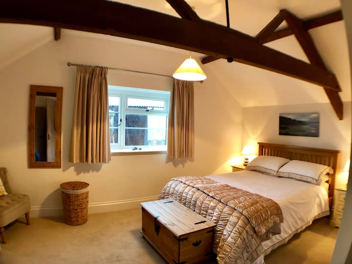 חדר שינה ראשי עם תקרה מקומרת וקורות מקוריות חשופות