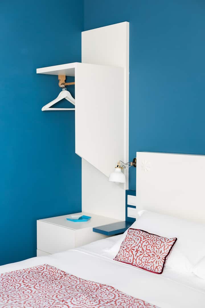La decoración privilegia un diseño limpio y funcional, como este estante para ropa al lado de la cama.