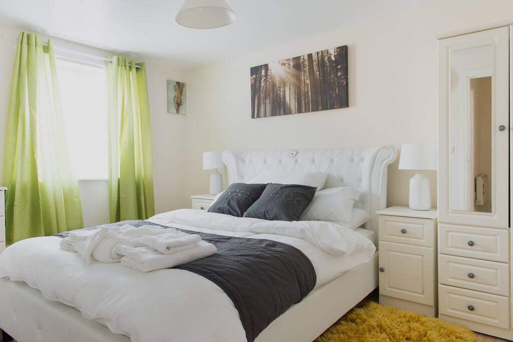 Dressed kingsize bed with green therapeutic window curtains etc