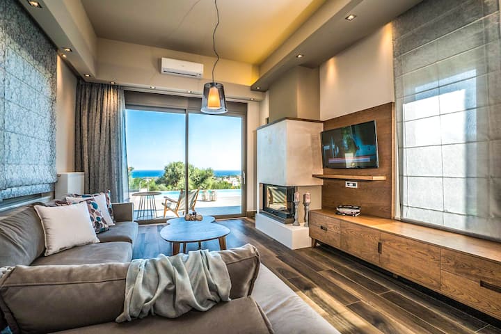 Open-plan living room with plush sofas, a dining area, and a fully equipped kitchen.