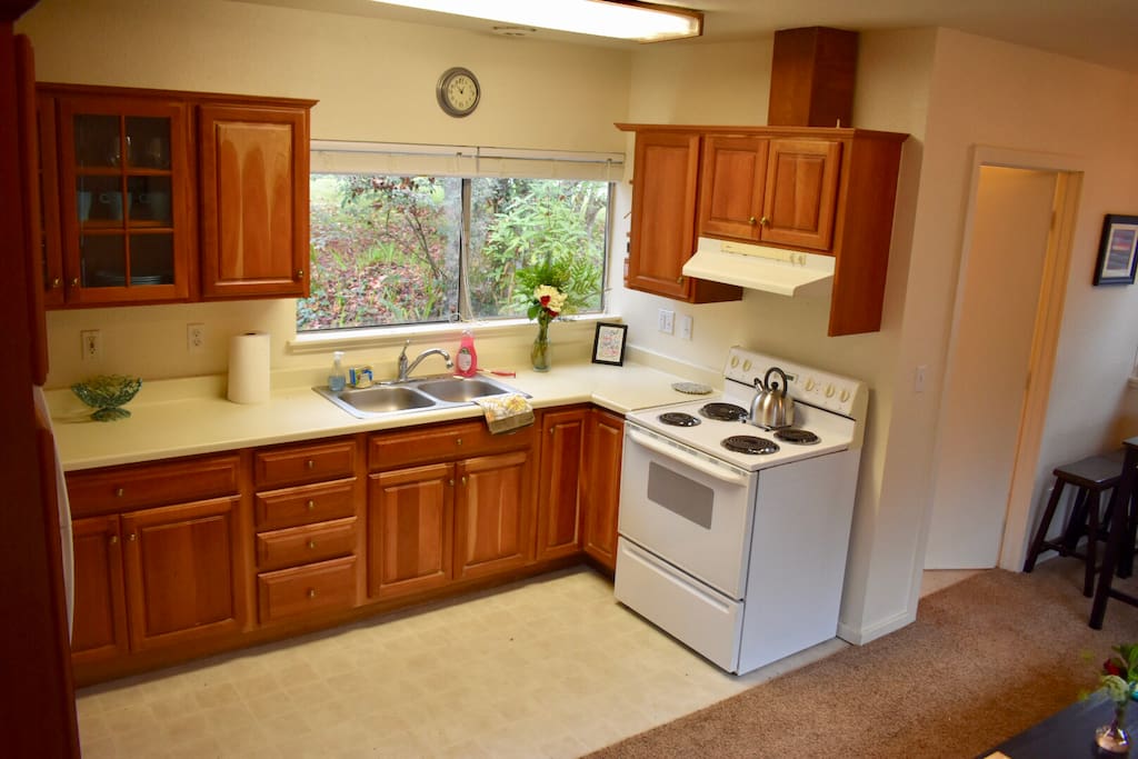 Kitchen with full size refrigerator, stove, oven, dishes & cooking needs with a foliage view