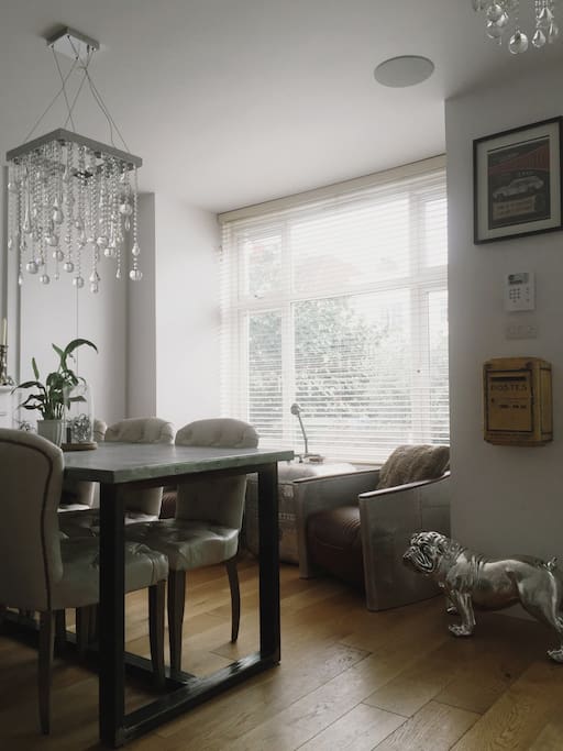 6 seater dining table and seating in bay window. View is of a small garden and the street. Open plan split by the staircase to floors above.
