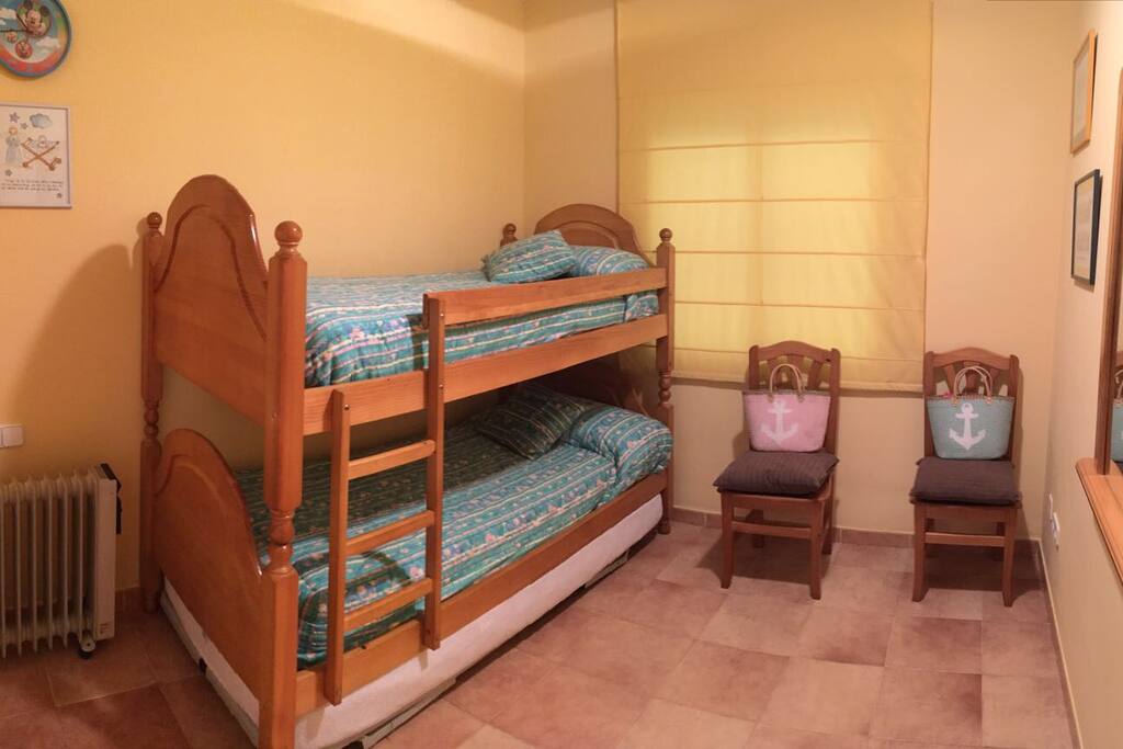 Dormitorio con tres camas y armario empotrado.