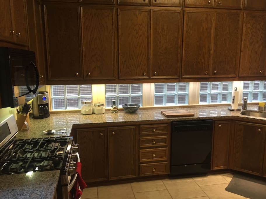 Spacious kitchen with gas-range stove, dual ovens, microwave oven, stainless steel fridge and ample counter space