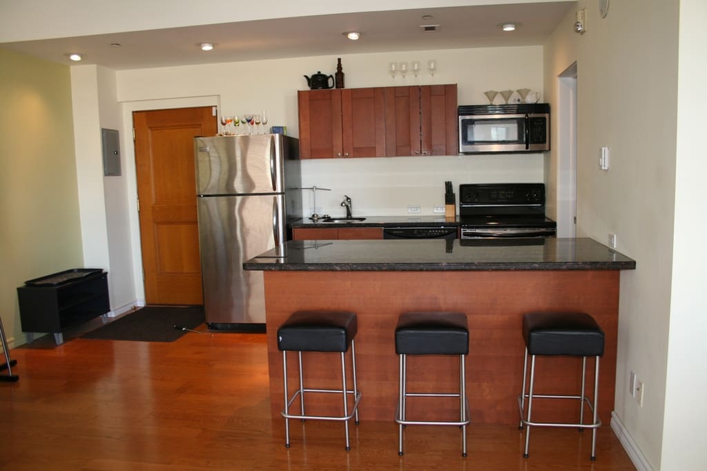 This is the kitchen, it has a sink, a microwave, and oven, with a stainless steel fridge complete with cutlery and cups.