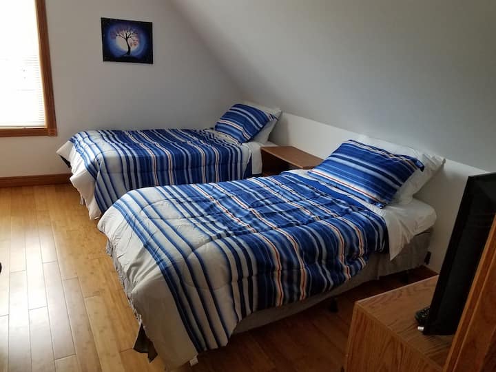 Спалня на горния етаж с 2 единични легла (на снимката) и 1 двуетажно легло. Двуетажното легло има матрак в пълен размер на долното легло и матрак с две единични легла на горното легло.