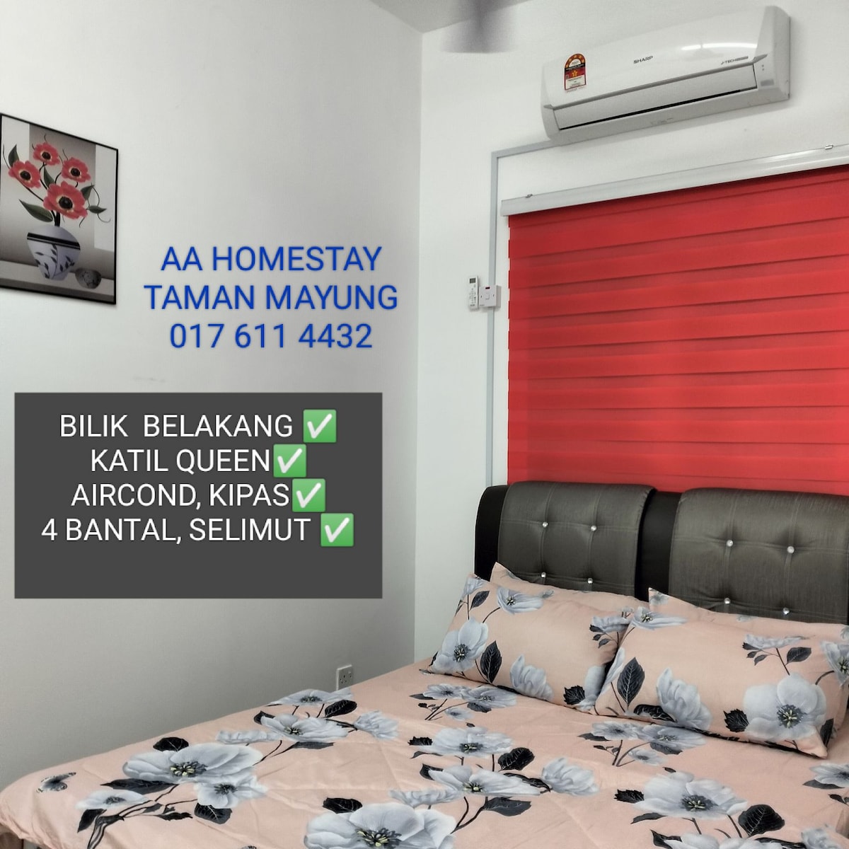 A cozy bedroom is featured with a spacious queen bed adorned with floral-patterned bedding. The room includes an air conditioning unit mounted above and a vibrant red blind covering the window, allowing for controlled natural light.