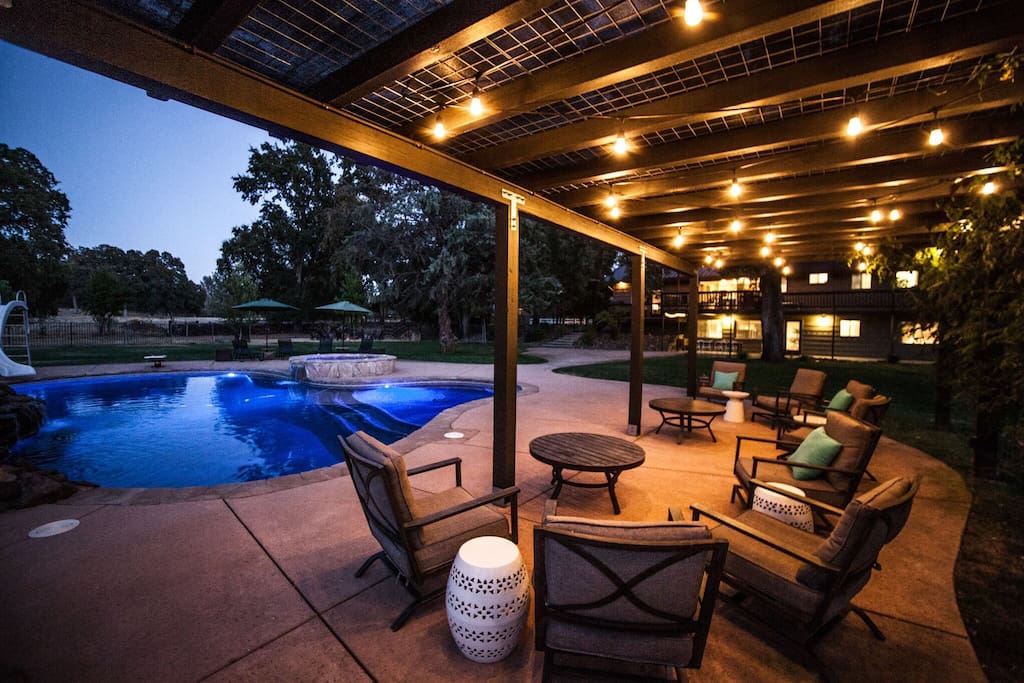 Wisteria-covered, lighted patio with seating by pool