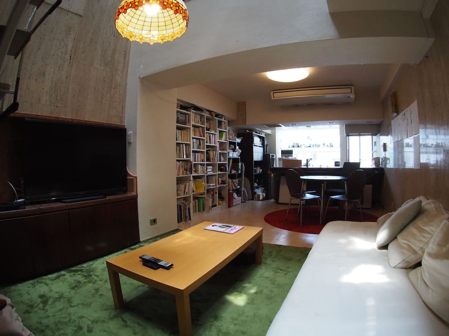 Living room equipped with large TV, sofa, chairs, and dining table, shared with 8 other residents