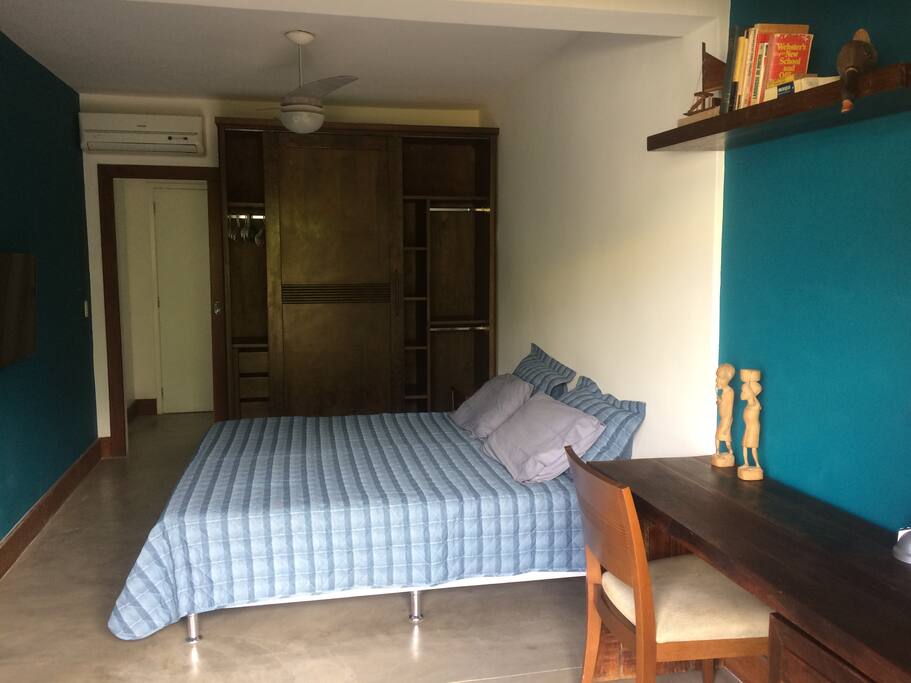 Interior do quarto com armário, mesa, ar condicionado e TV