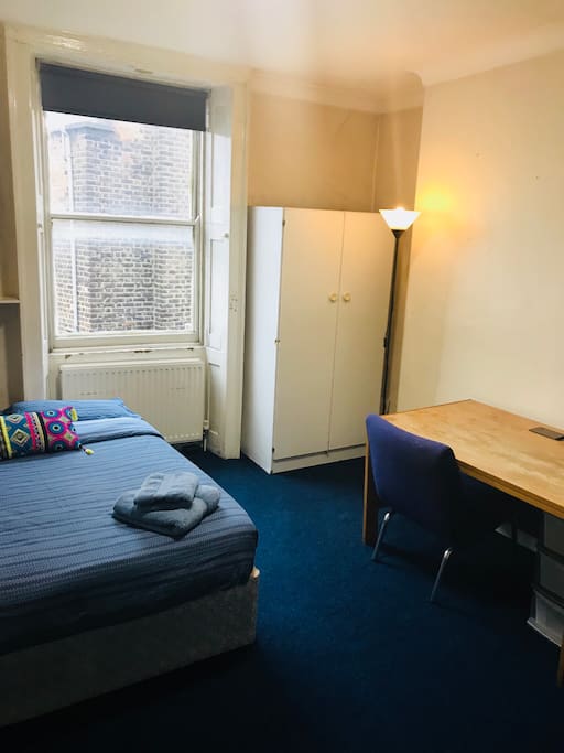 The room has a double bed, desk and wardrobe.