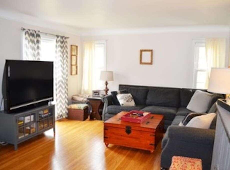 First floor living room with spacious couch and large window.