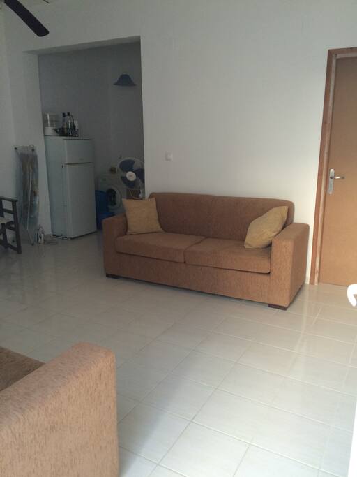 This is the main lounge , one double and one triple sofa. Table and four chairs . Information provided. Games and books available for use. Tiled floor with ceiling fan.