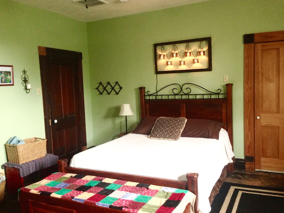 Queen bed, extra blankets and extra light-blocking curtain (for balcony door as desired) in bench at foot of bed, small closet with hangers to right.