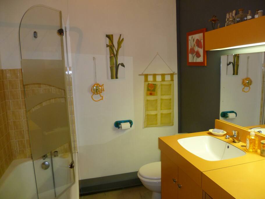 Salle de bain avec baignoire, lavabo, WC, meuble de rangement.