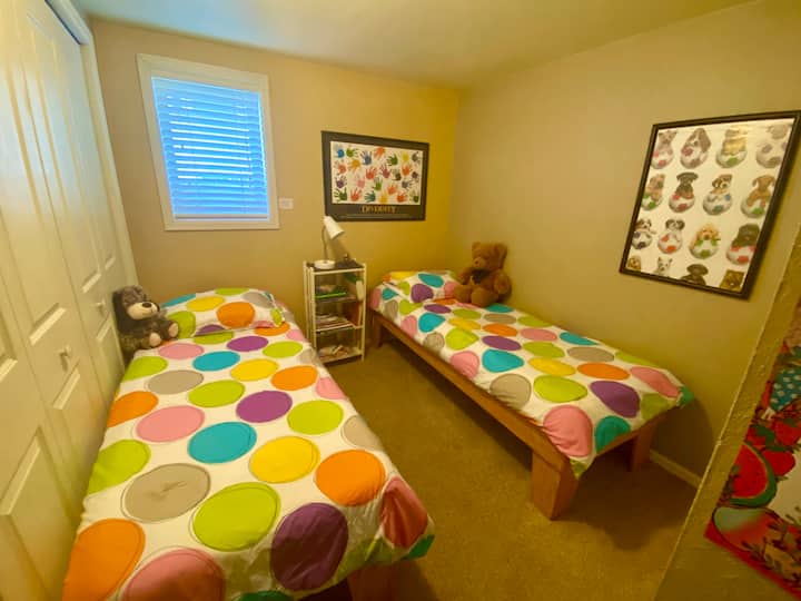 Kinderkamer ingericht. Twee smalle, twee eenpersoonsbedden en boeken. De kast is inclusief basketbalring, baby-/peuteruitrusting, pack n play en leuke dekens.