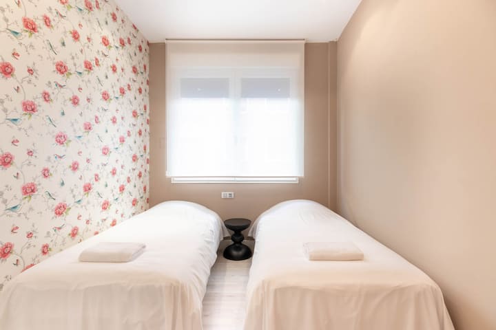 Chambre double équipée de deux lits simples avec une vente qui permet l'accès à la lumière naturelle de la rue.