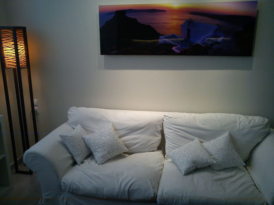 The printed photograph of Santorini above the couch reminds one of the greek paradise islands