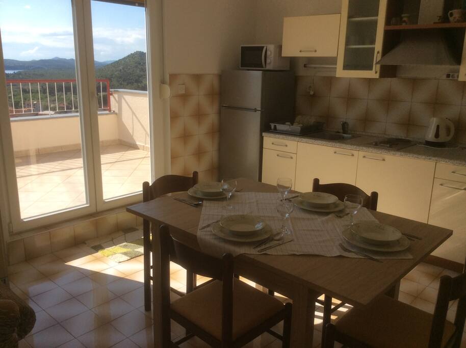 Kitchen with Fridge, sink, stove, microwave, dishes, cutlery, glasses, cups