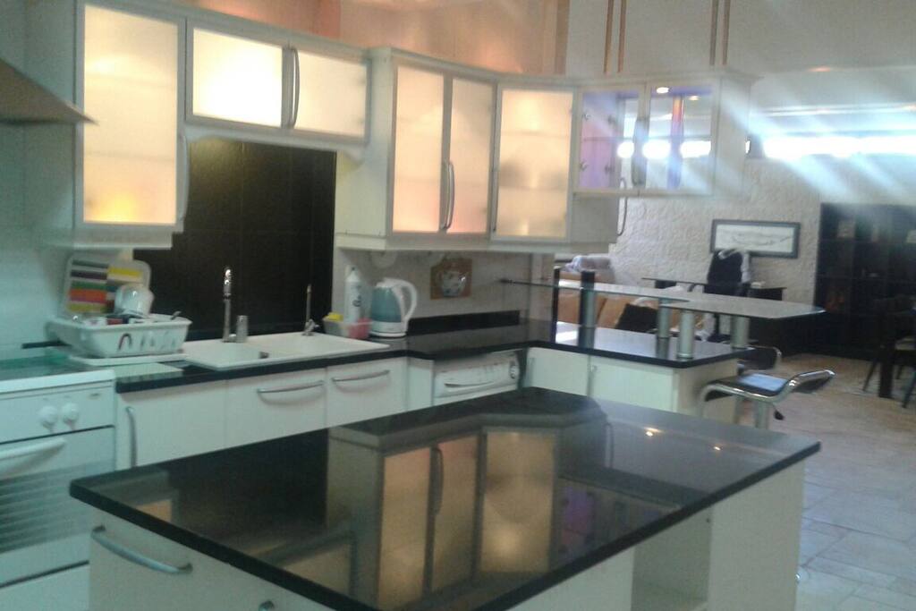 Open kitchen with plates, dishes, cutlery, and kettle.