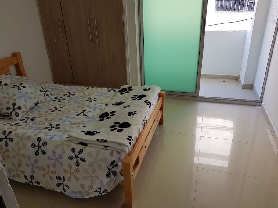Habitación con cama doble, armario, baño compartido y balcón.