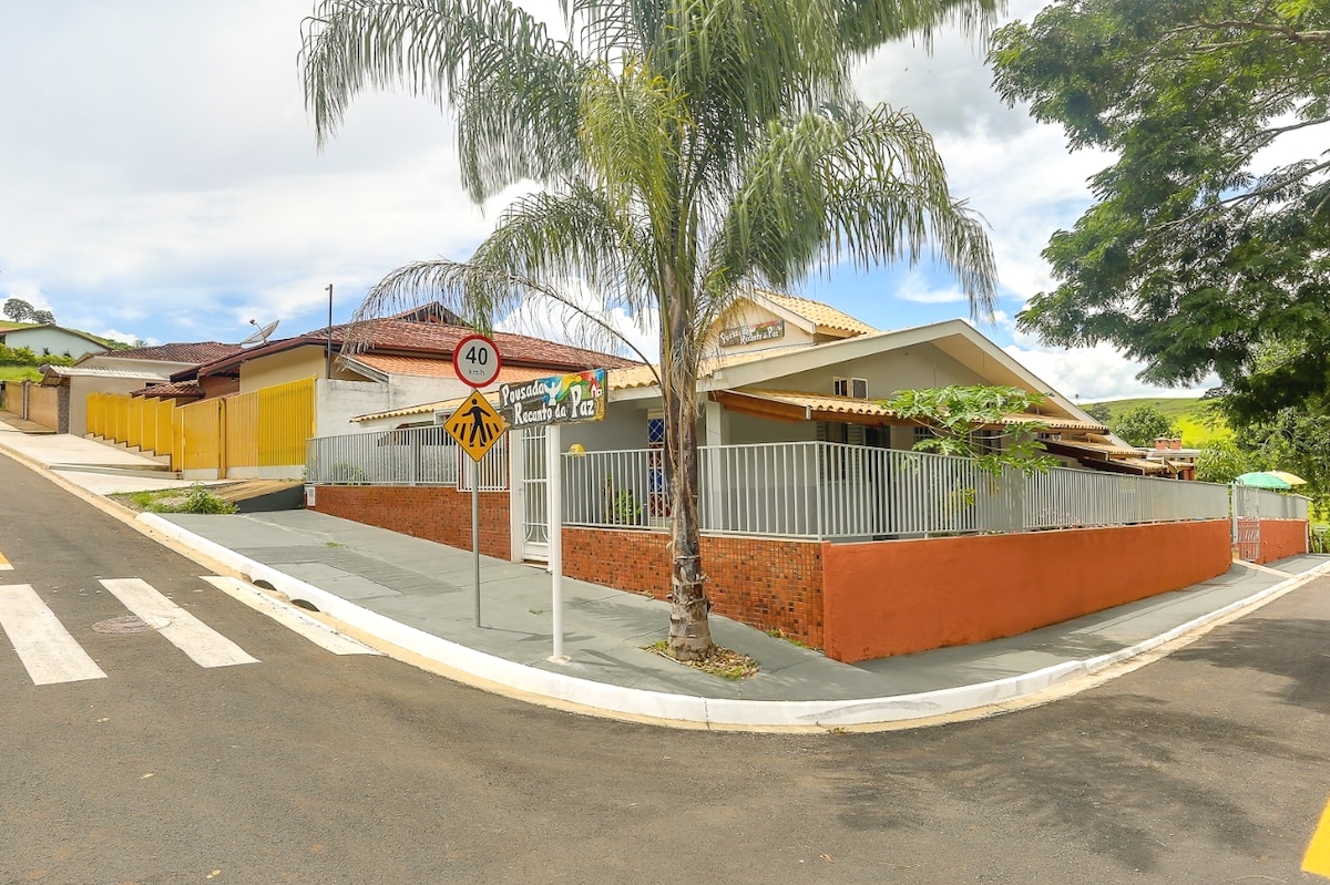 The exterior view of the property showcases a single-story building surrounded by a fence. Lush palm trees are visible in the foreground, along with a clear road sign indicating a speed limit. The setting reflects a quiet neighborhood with nearby greenery.