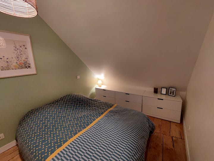 Dormitorio 2 situado en altillo separado de la planta baja por una cortina para mayor privacidad con una cama de 140 cm, sábanas, almohadas, armario, muebles de almacenamiento bajos y lámpara de noche