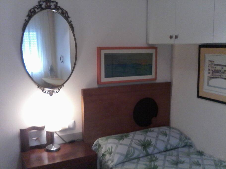 Habitación exterior privada con espejo y mesita de noche.