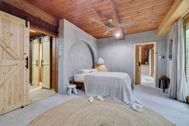 Main floor bedroom with queen bed, workspace and comfy chair. 