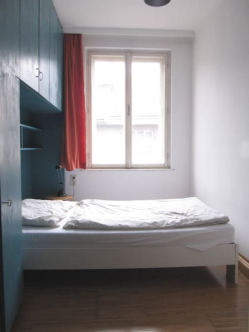 The bedroom has one window as well as a wall unit with shelves providing a lot of storage space.