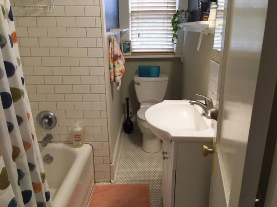 The early 20th century bathroom is updated with period appropriate subway tile, tile floors, and original art on luminous dark blue walls.