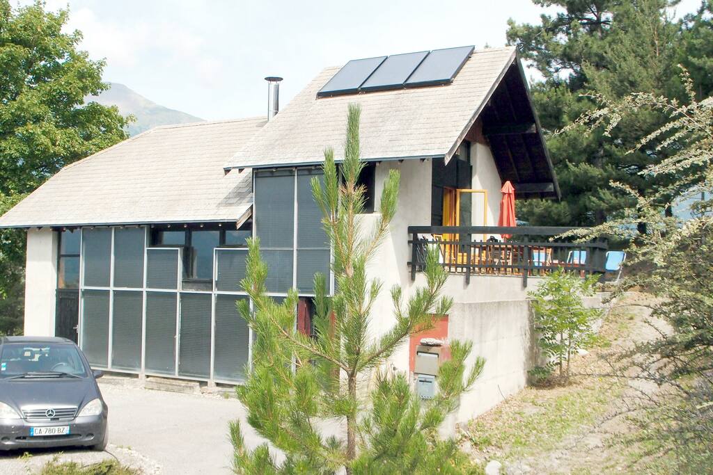 La maison à 2 niveaux (+séjour en demi-étage), plateforme parking-pétanque à gauche, terrasse et jeux à doite