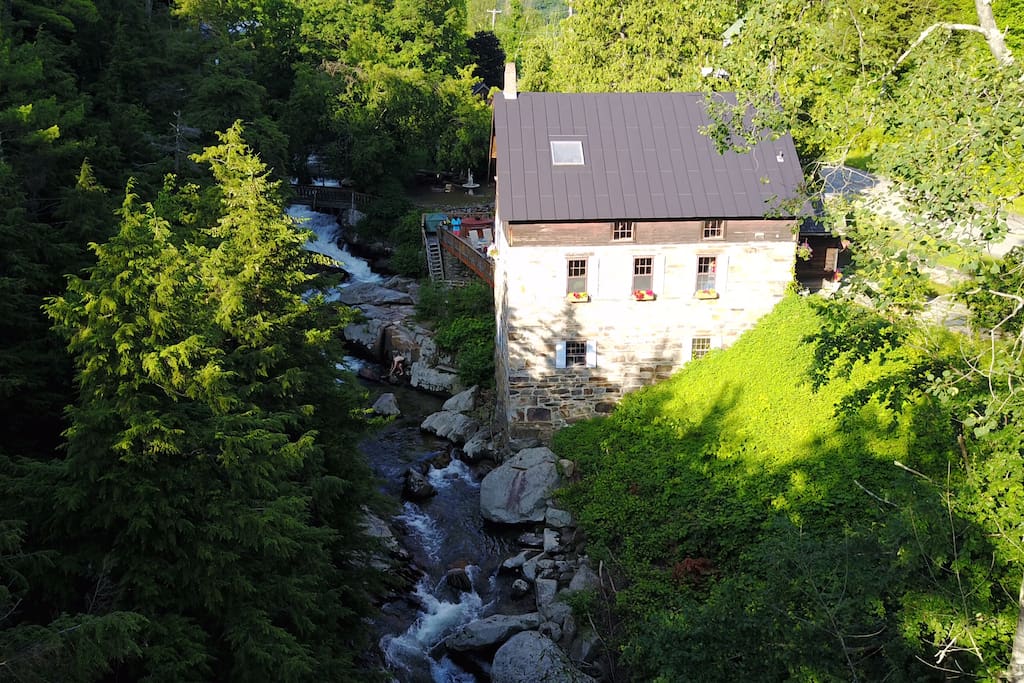 Aerial view looking upstream at the Millhouse, the footbridge and the campsite "Cozy Screen House on a Waterfall".