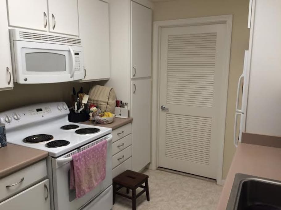 Kitchen, complete with dishes, utensils and dishwasher. Laundry room behind white door for in unit laundry.