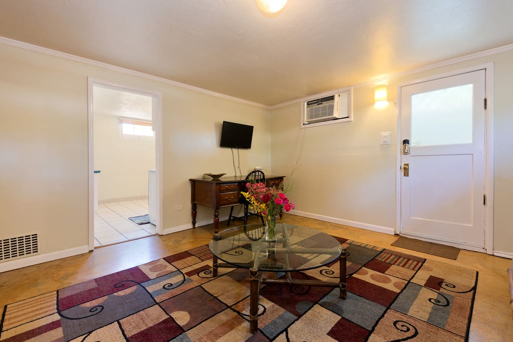 Living room with large desk and TV w/ HDMI/DVD and wall heater and A/C