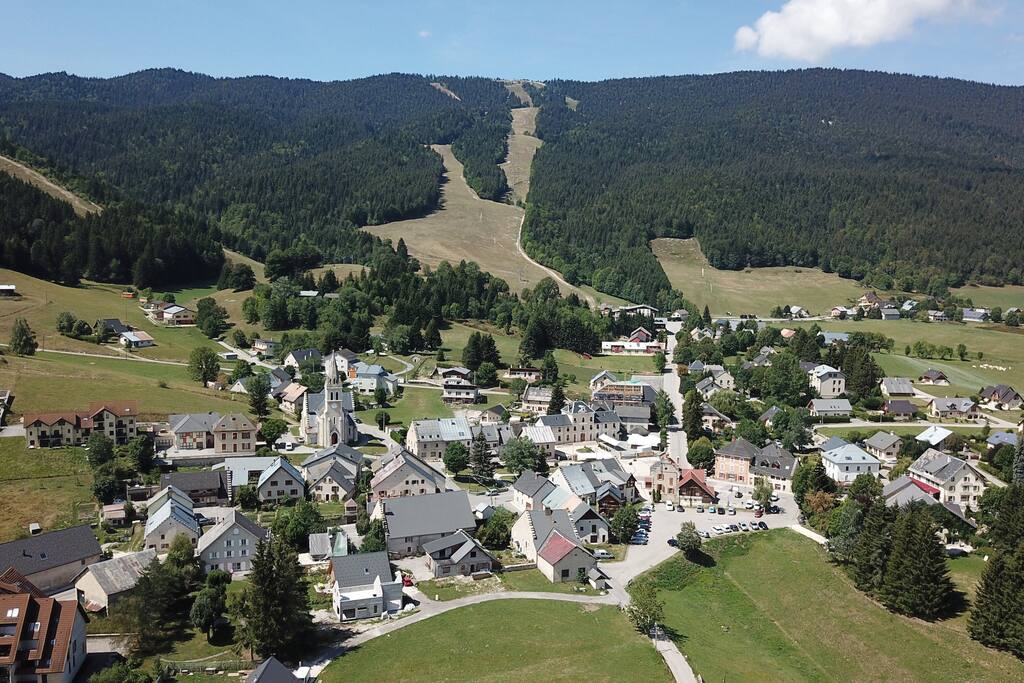 Le jolie village de Méaudre avec les Chatelard au loin et les pistes de ski en arrière plan.