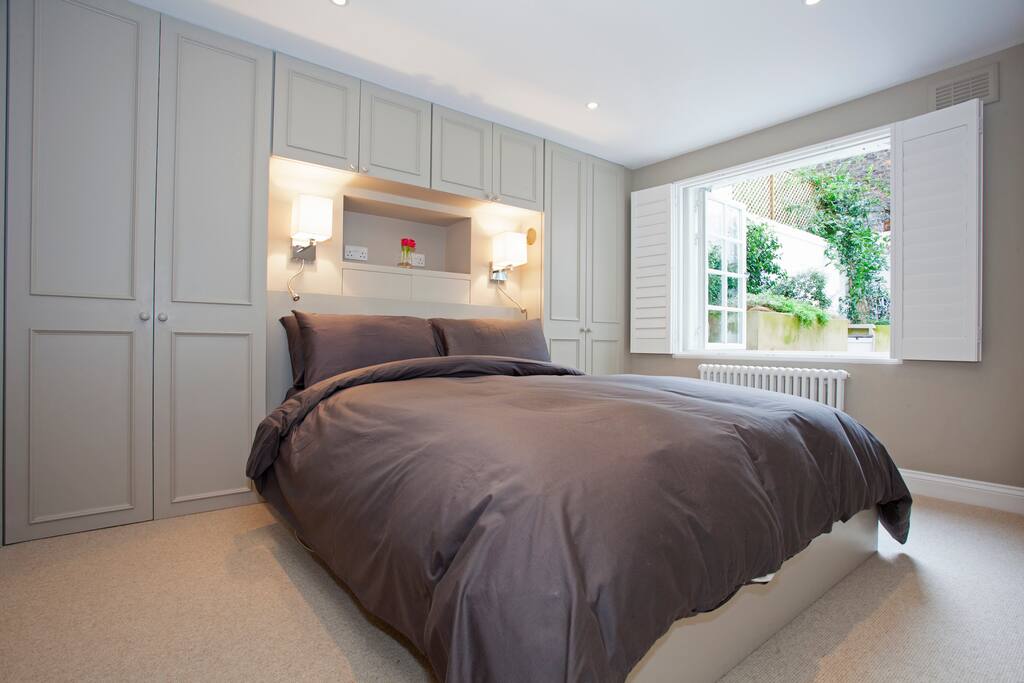 Back bedroom with kingsize bed, built in reading lights and floating mullion windows out to quiet courtyard garden
