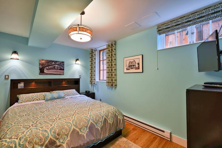 California King bed with individually controlled reading lights above the headboard.  Another smart TV on the wall at right.