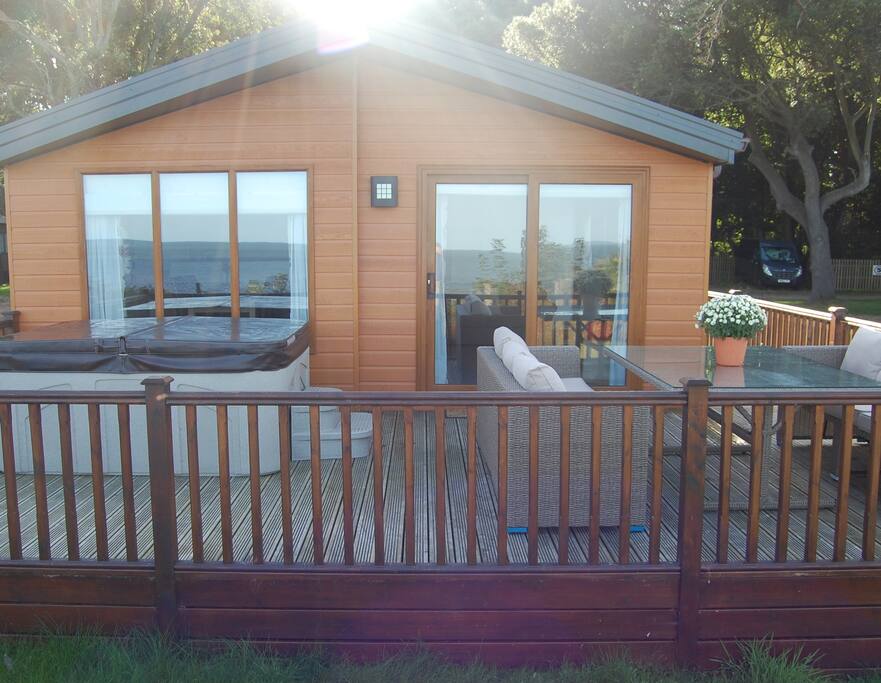Decking with Hot tub and furniture overlooking sea.