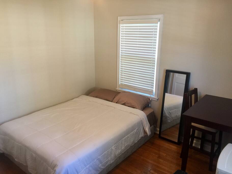 Guest bedroom. Queen size bed, refrigerator, desk/table, and closet with plastic dresser.