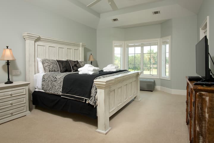 Брачна спална соба со поглед на терен за голф и пристап до балкон