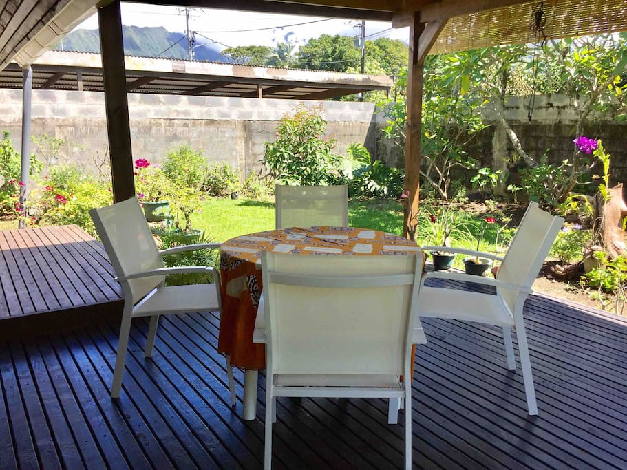 Terrasse couverte avec table à manger et petit jardin fleuri