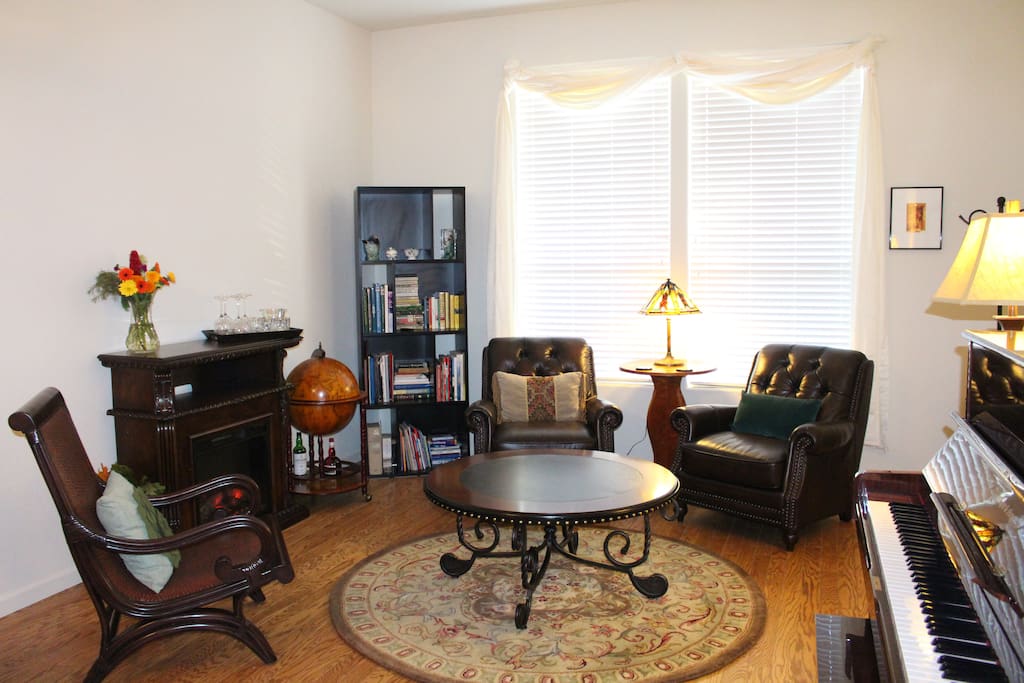 Private sitting room with piano and electric fireplace.