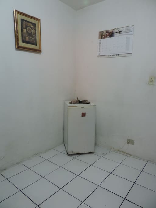 Pequeño cuarto con un mueble de bar y un mini refrigerador
