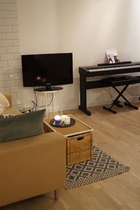 The apartment has both TV, piano and guitar