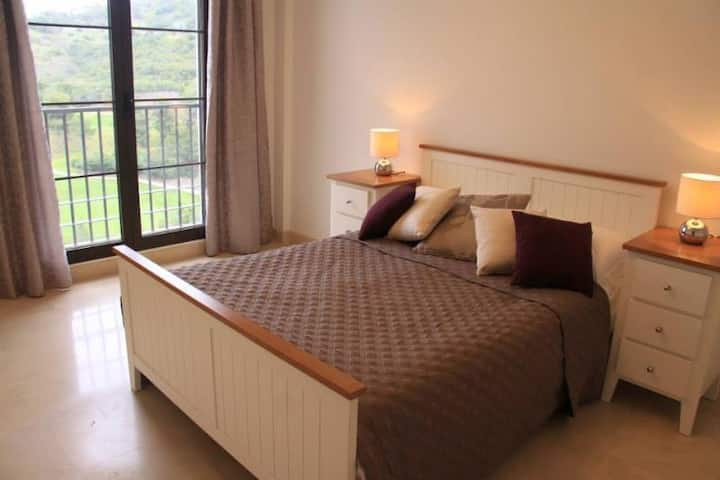 Dvokrevetna soba s  balkonom i pogledom na teren za golf i planinu.