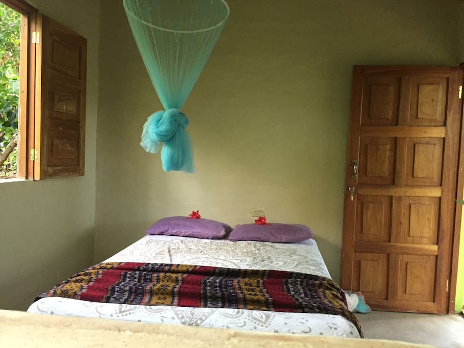 Simplicity. Comfortable double bed with mosquito net, small table and fan.