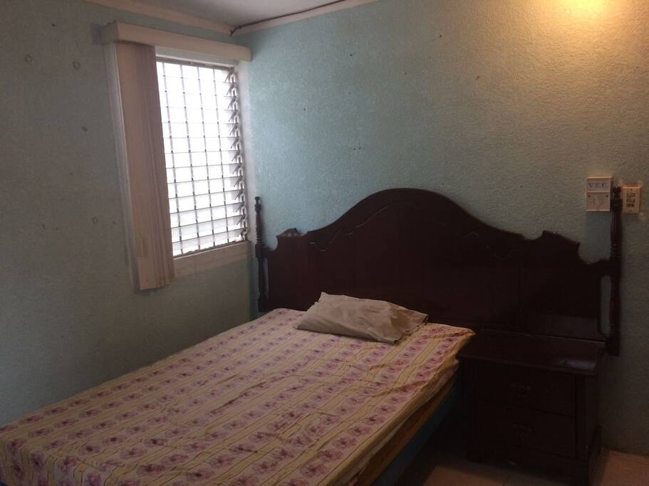 Habitación privada con una cama matrimonial, toallas, sillas, ventilador y hamaqueros.