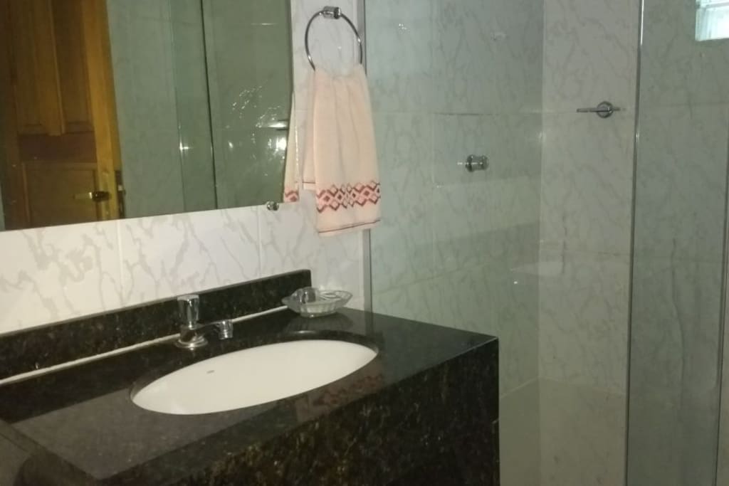 Banheiro com chuveiro elétrico e box blindex. Oferecemos roupa de banho.