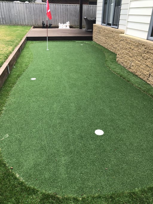 Synthetic 4 hole golf green with putters and balls
